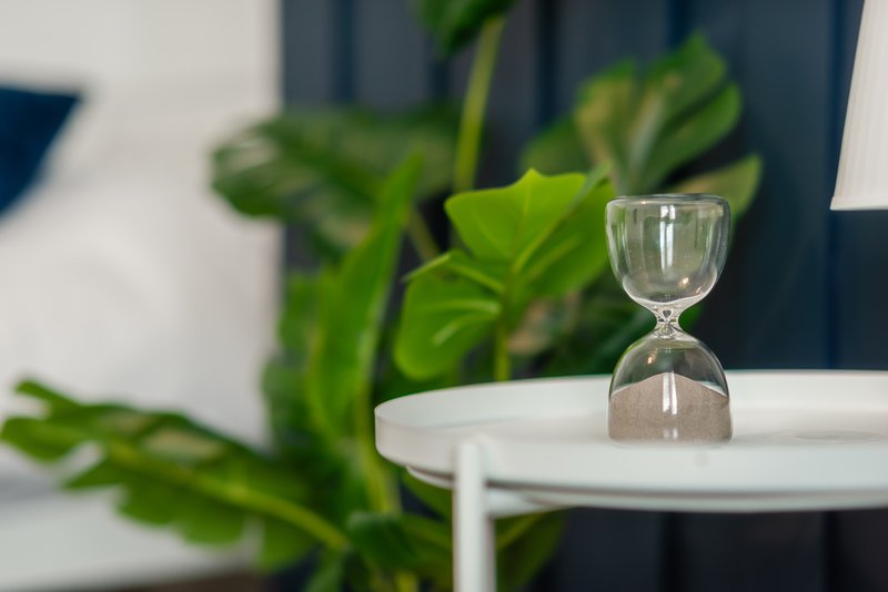 Modern table setting with hourglass, potted plant, and white plate