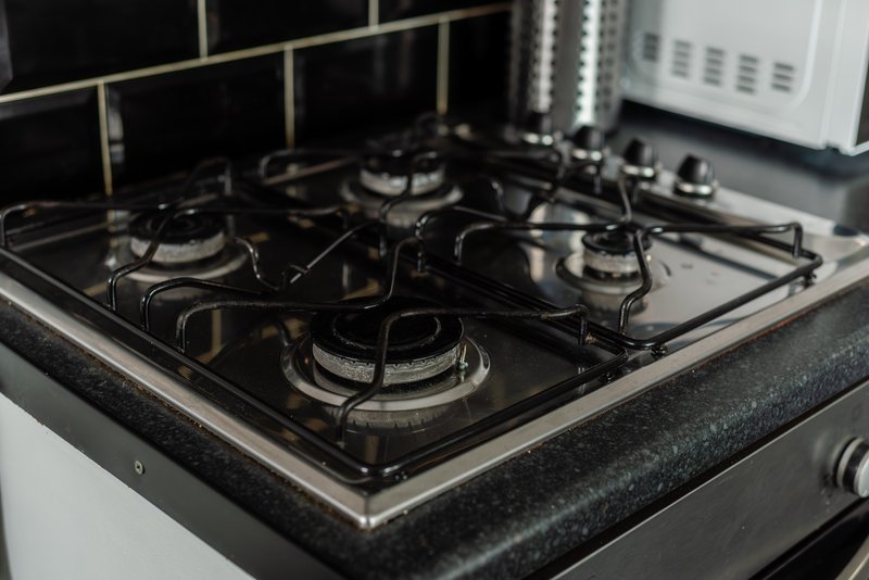 Black gas stovetop with four burners and stainless steel trim in kitchen