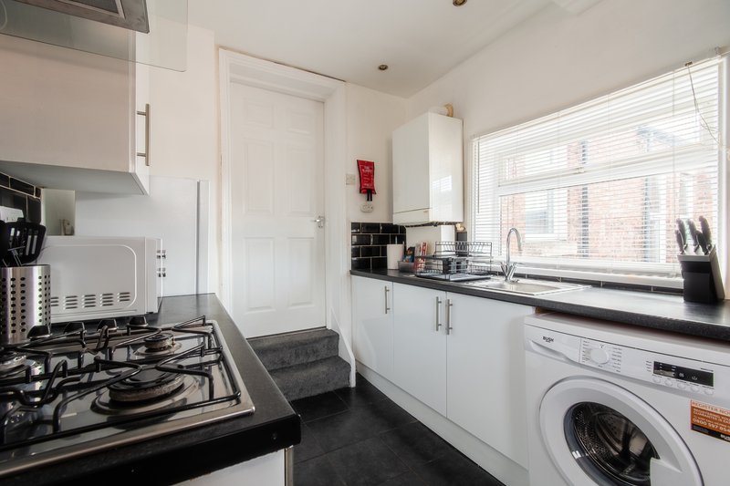 Modern kitchen with white cabinetry, gas hob, dishwasher, washing machine and window