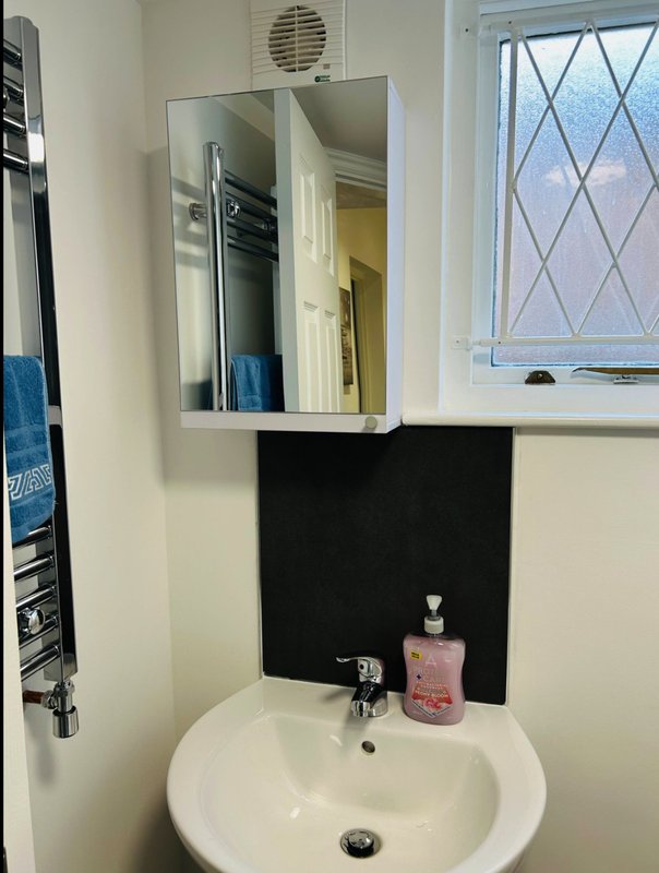 Bathroom sink with mirror cabinet, soap dispenser, and window with diamond-patterned glass