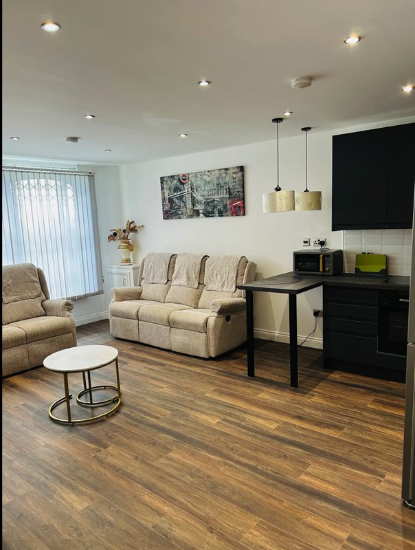 Modern living room with beige sofa, wooden flooring, pendant lights, and wall-mounted TV