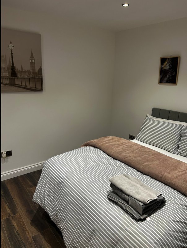 Bedroom with double bed, striped bedding, brown throw, and wall art