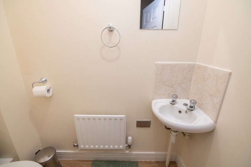 Small bathroom with corner sink, radiator, towel ring and toilet paper holder