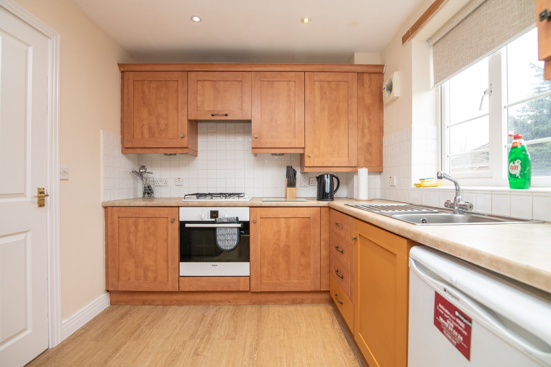 Modern kitchen with wooden cabinets, white countertops, gas cooktop and stainless steel appliances