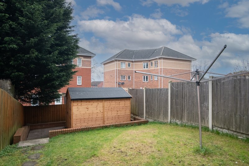 Residential backyard with brick garage, wooden fence, and neighboring two-story brick house
