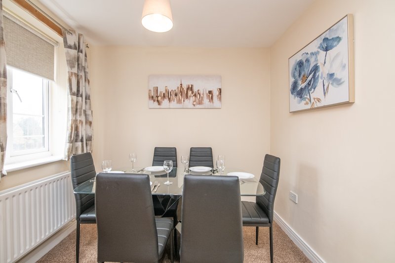 Dining room with black table, gray chairs, window with patterned curtains and wall art