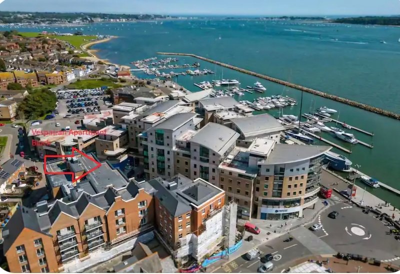 Aerial view of waterfront residential buildings with marina and boats below