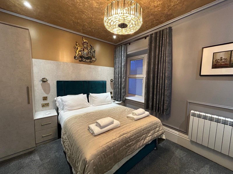 Modern bedroom with double bed, teal headboard, ceiling light fixture and framed wall art