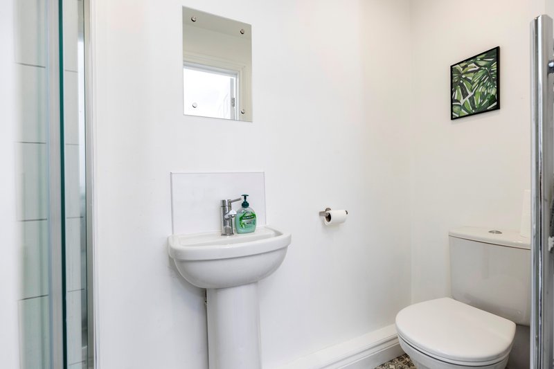 Clean bathroom with pedestal sink, toilet, mirror and small window