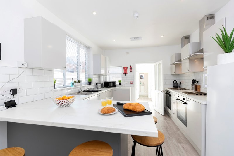 Modern kitchen with white cabinetry, island counter, and fresh produce displayed