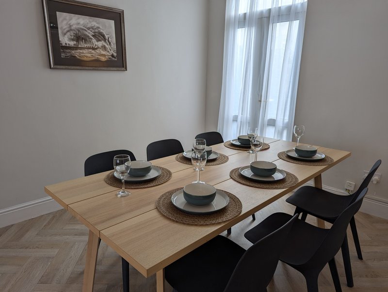 Dining room with wooden table, black chairs, place settings, and framed wall art