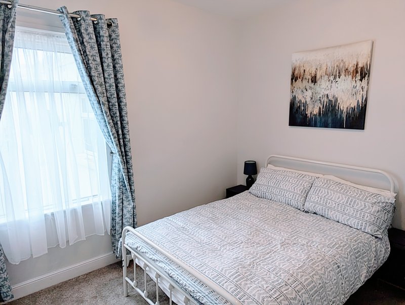 Bedroom with double bed, white metal frame, patterned bedding and wall art