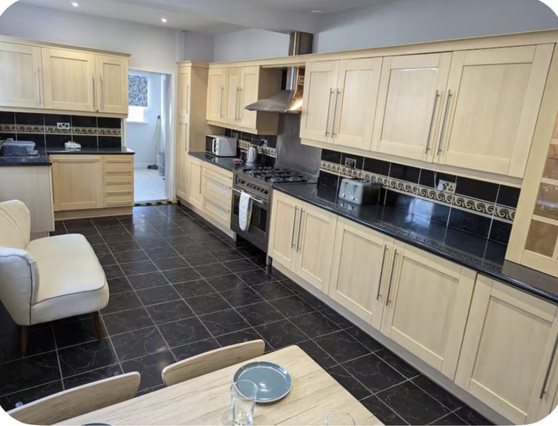 Modern kitchen with cream cabinets, black tiled floor, stainless steel appliances and dining table