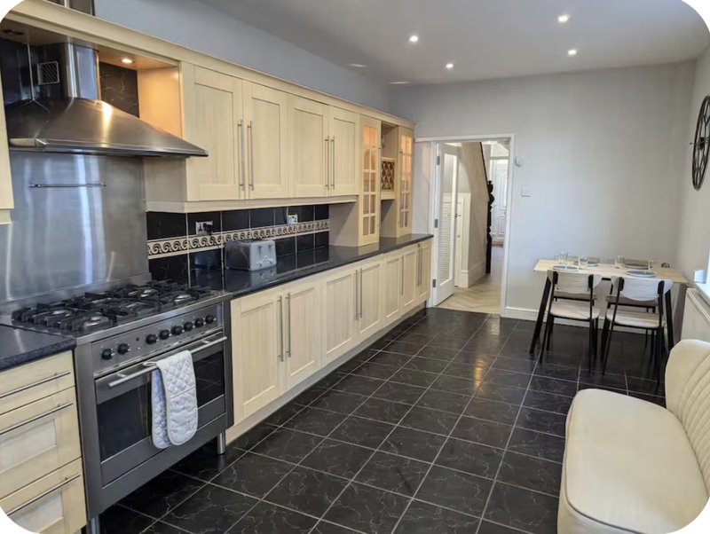 Modern kitchen with cream cabinetry, stainless steel appliances, black countertops and dining area