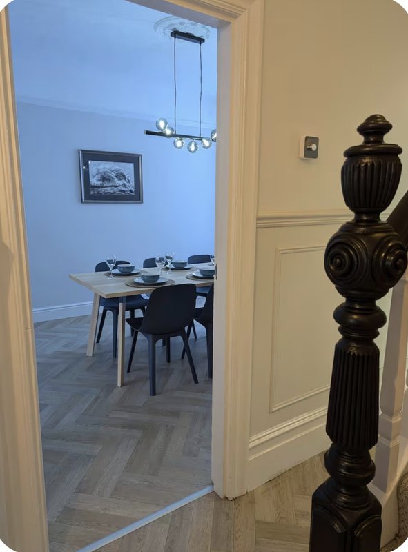 Modern dining room view through open doorway with table, chairs, pendant light and artwork