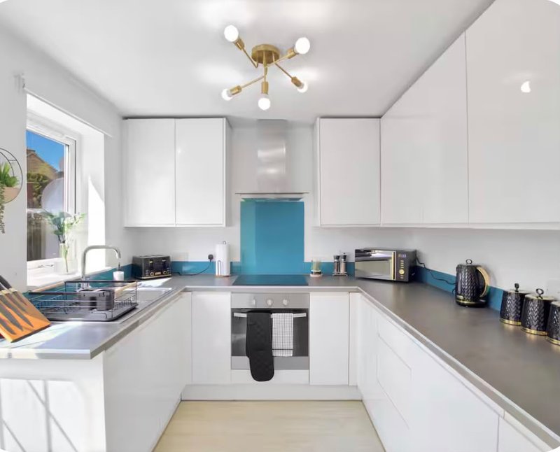 Modern white kitchen with blue accents, stainless steel counters and integrated appliances