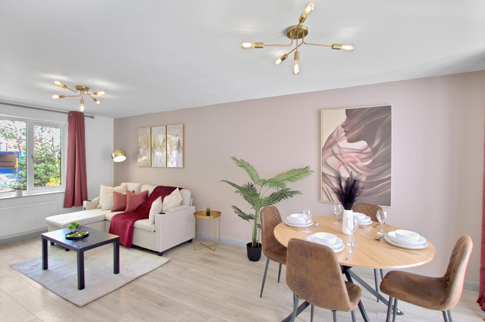 Open-plan living and dining area with cream sofa, dining table, pink walls and modern lighting