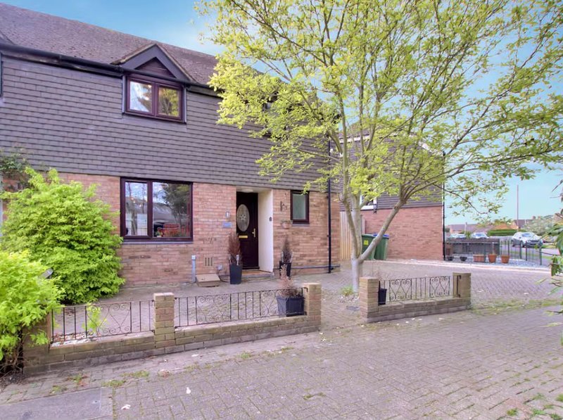 Brick and timber-clad house with driveway, front garden, and mature trees
