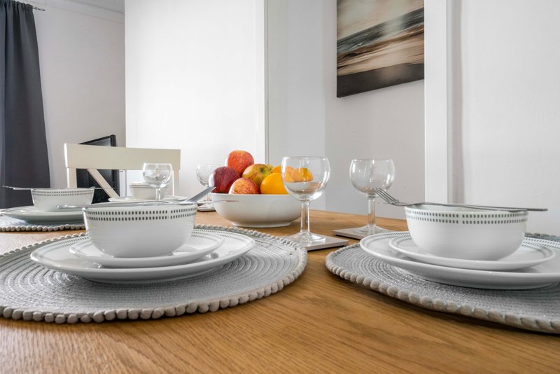 Dining table set for two with white place settings, wine glasses, and fresh fruit centerpiece