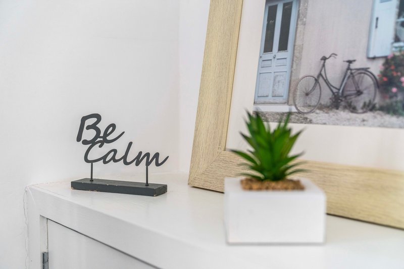 White shelf with decorative metal sign, potted plant, framed photograph and wooden frame