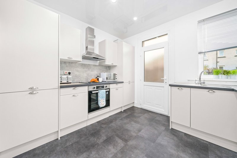 Modern kitchen with white cabinetry, stainless steel appliances, and dark gray flooring