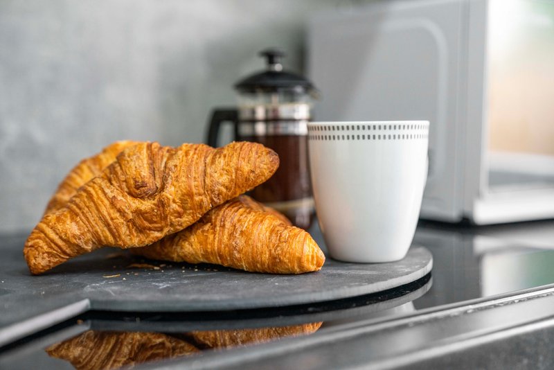 Kitchen counter with croissants, white mug, and blurred appliances in background