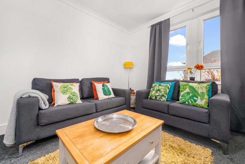 Modern living room with grey corner sofas, wooden coffee table and mountain view through large windows