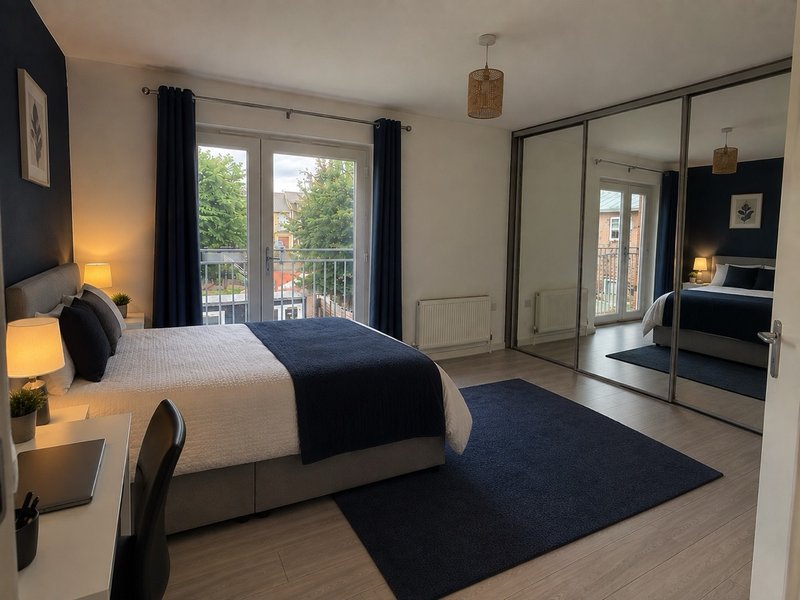 Modern bedroom with double bed, mirrored wardrobe, blue rug and balcony access