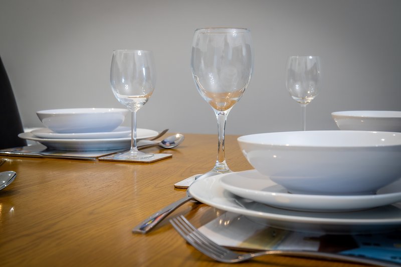 Formal dining table set with white dishes, wine glasses, and cutlery