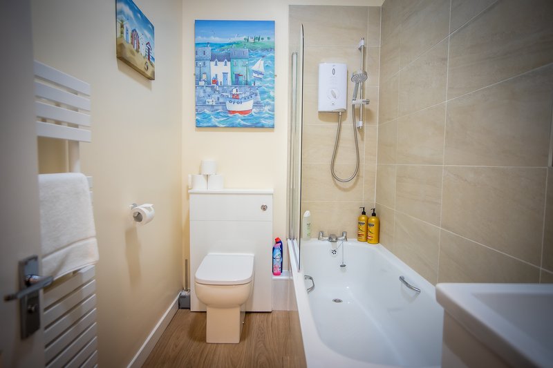 Modern bathroom with toilet, bathtub, shower enclosure, and wall-mounted artwork
