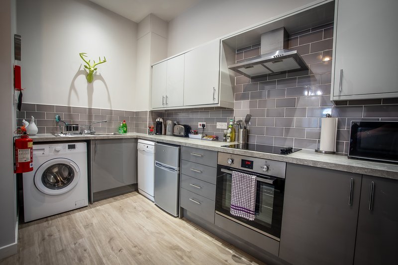 Modern kitchen with grey cabinetry, stainless steel appliances, washing machine and tiled backsplash