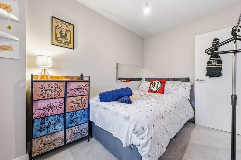 Bedroom with double bed, colorful dresser, lamp, and wall-mounted shelving unit