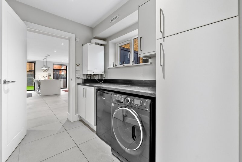 Modern utility room with washing machine, wall-mounted boiler, and storage cabinets