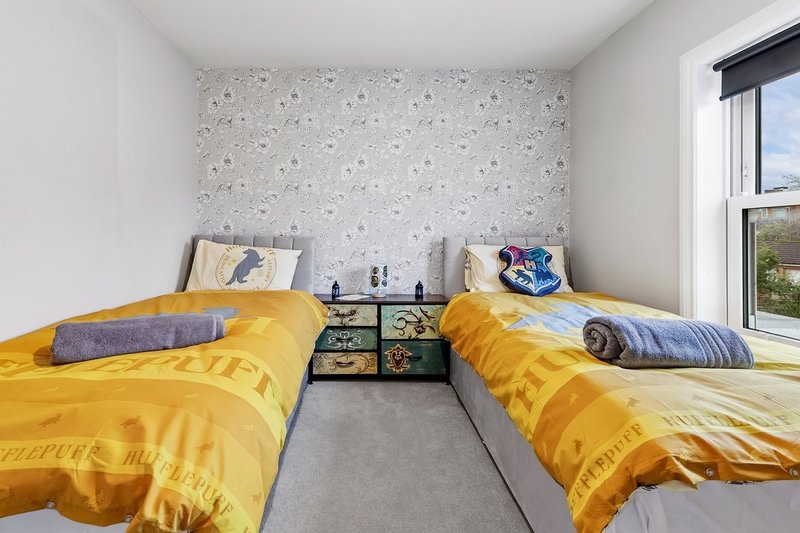 Twin bedroom with yellow bedding, decorative pillows, shared nightstand, and large window