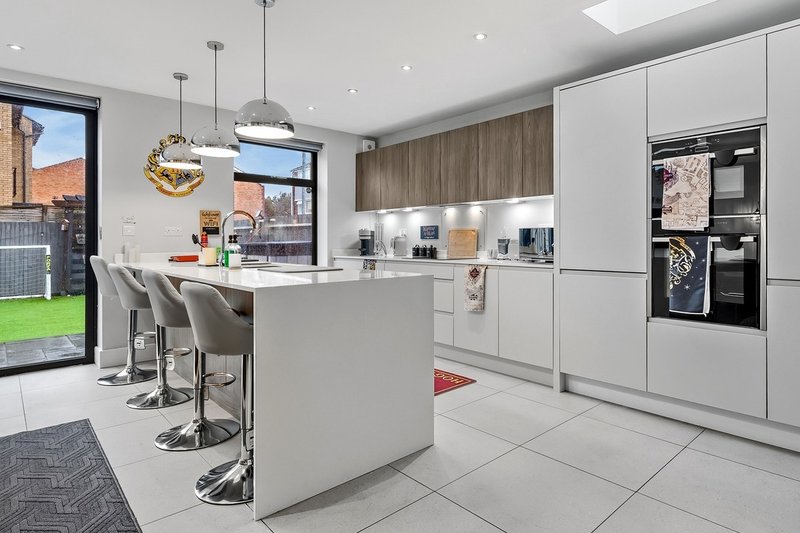 Modern kitchen with white cabinetry, island seating, stainless steel appliances and garden view