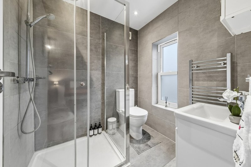 Modern bathroom with walk-in shower, toilet, white bathtub, heated towel rail and window