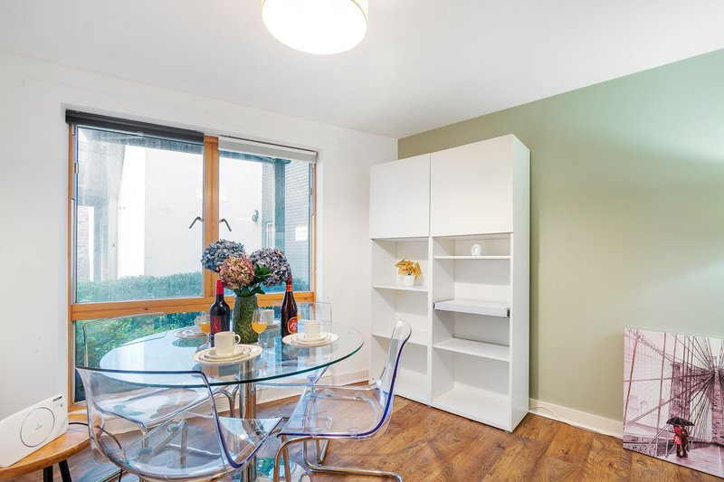 Bright apartment room with dining table, transparent chairs, white storage unit and balcony view