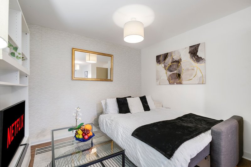 Modern bedroom with double bed, black throw, wall art, fireplace and ceiling light