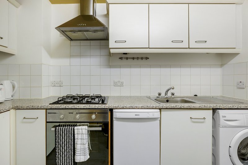 Modern kitchen with white cabinetry, gas cooktop, dishwasher and washing machine