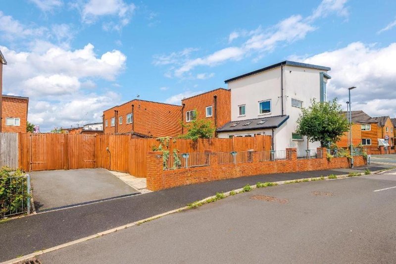 Modern brick residential building with driveway, wooden fence and street frontage