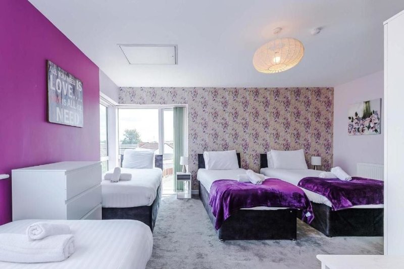 Bright bedroom with purple accent wall, twin beds, double bed, and floral wallpaper
