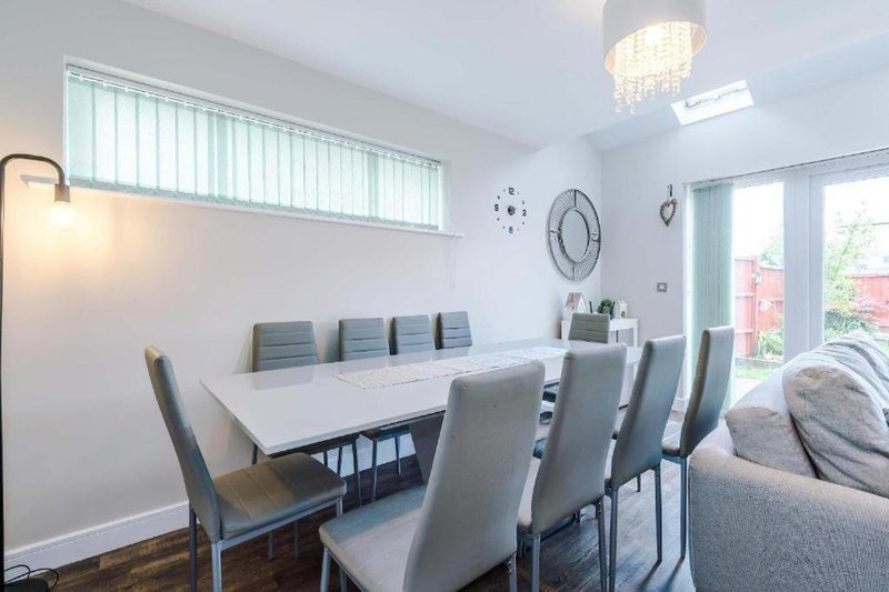 Modern dining room with white table, grey chairs, chandelier and wall clocks