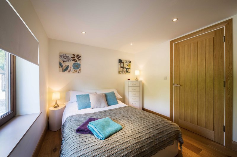 Bright bedroom with double bed, wooden wardrobe, bedside lamp and window seat
