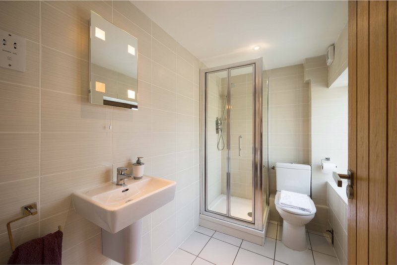 Clean modern bathroom with pedestal sink, enclosed shower cubicle, toilet and mirrored cabinet