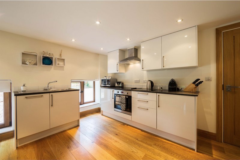 Modern kitchen with white cabinets, black countertops, stainless steel appliances and wooden flooring