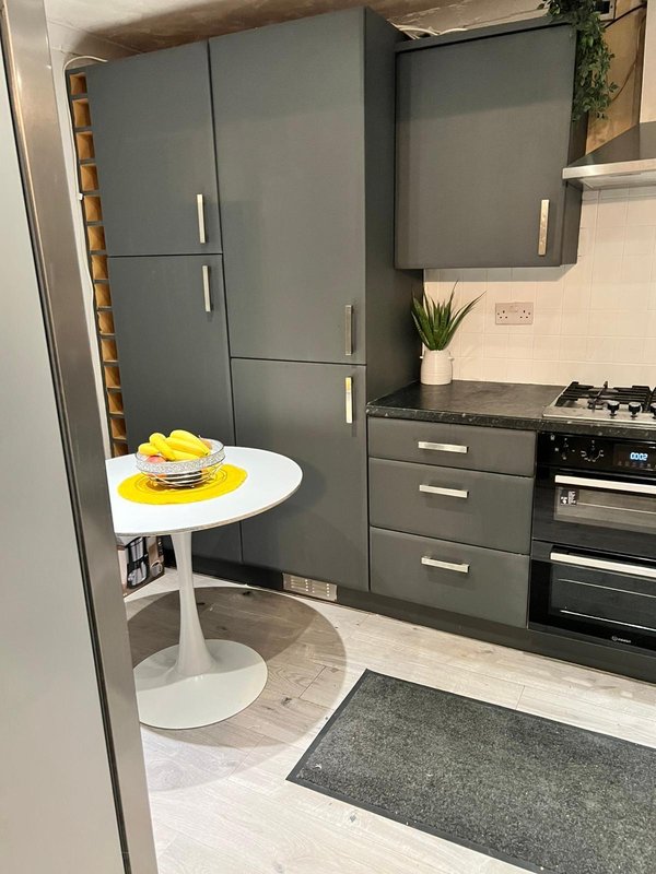 Modern kitchen with grey cabinetry, black appliances, white round dining table with yellow accents