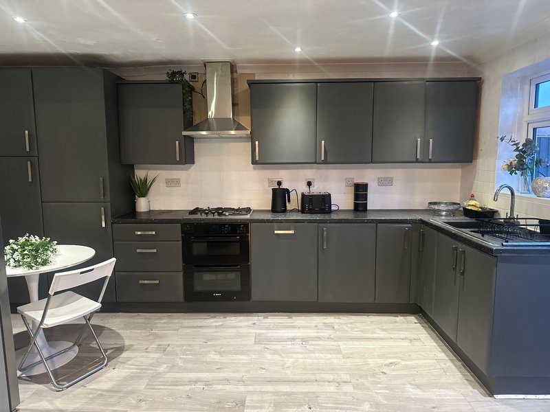 Modern kitchen with dark grey cabinetry, black appliances, light countertops and dining area