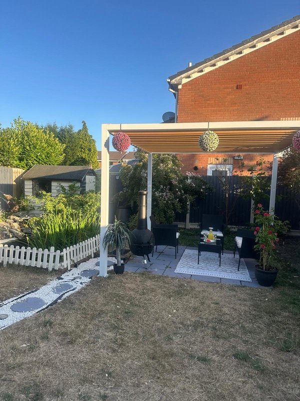 Brick house with covered patio, pergola, garden seating area and lawn