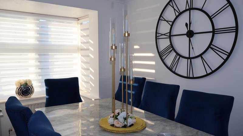 Modern dining room with navy chairs, marble table, large wall clock and pendant lights