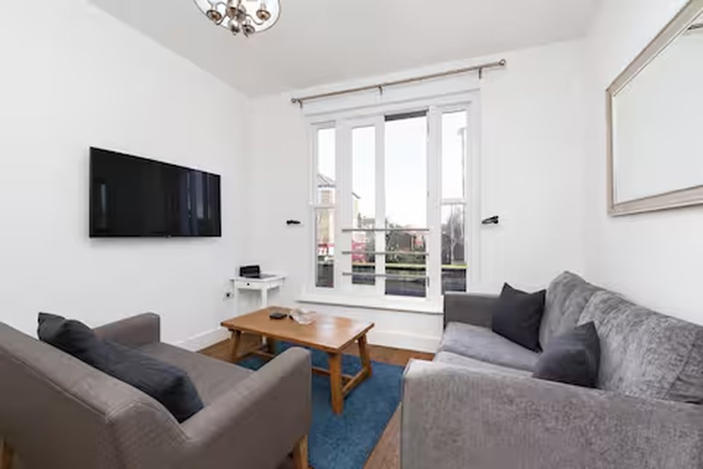 Modern living room with grey sofas, wooden coffee table, wall-mounted TV and patio doors